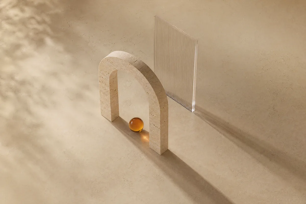 A travertine arch beside a clear glass panel with a small amber glass sphere at its base