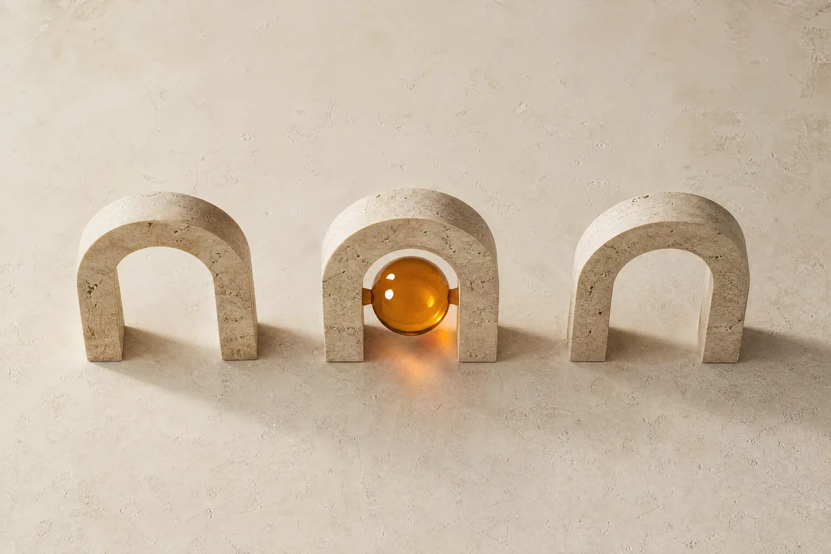Three travertine arches in a row, the middle one holding an amber glass sphere